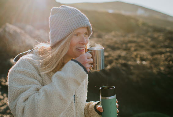 	Kvinna som gillar friluftsliv och dricker kaffe ute i naturen.