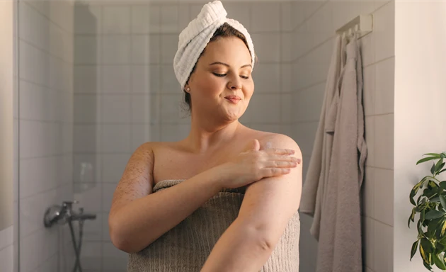En kvinna som smörjer in sin arm med hudlotion.