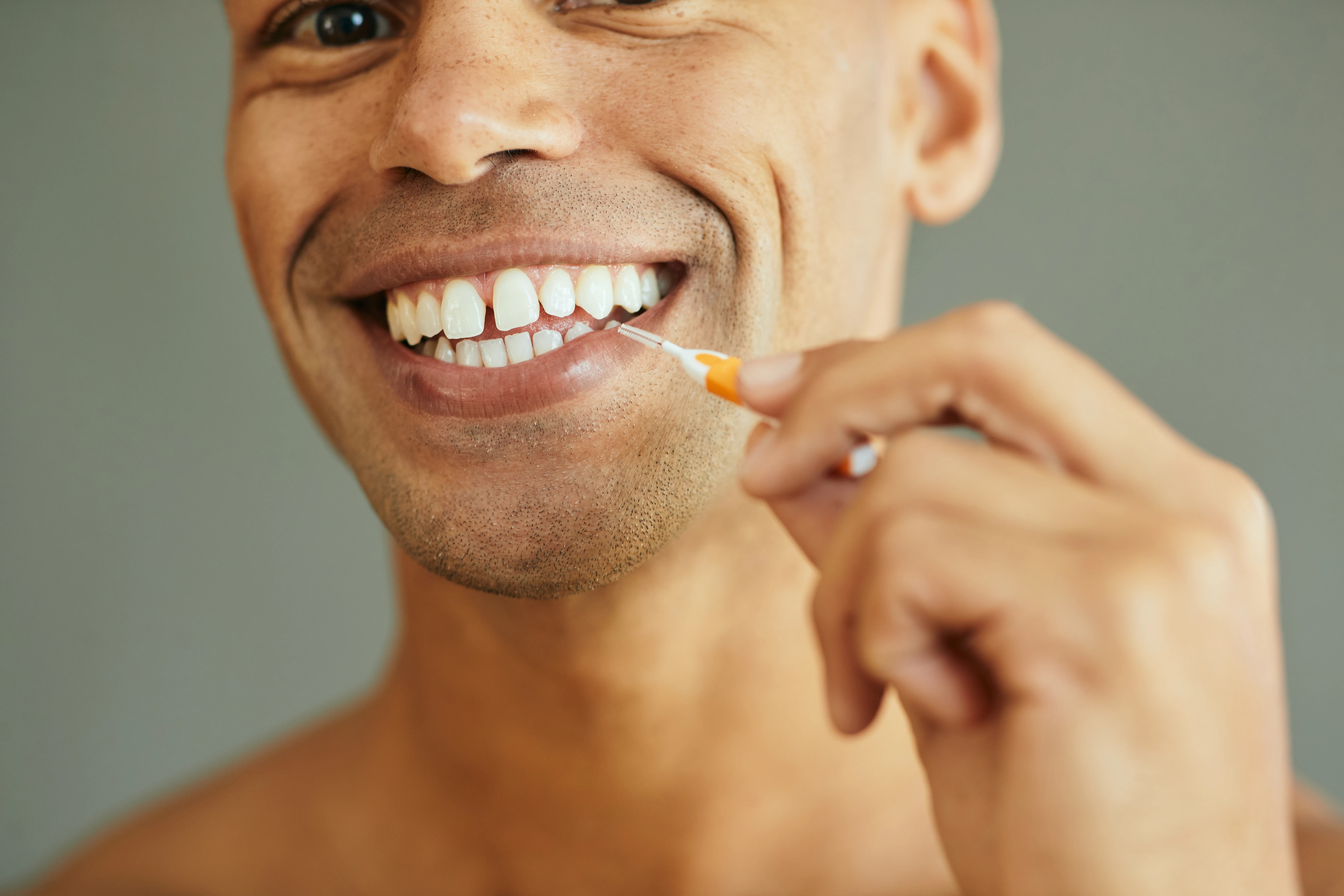 En man som rensar tänderna med en mellanrumsborste. 