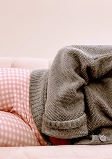 En person ligger i en soffa och håller ena handen på sin mage.