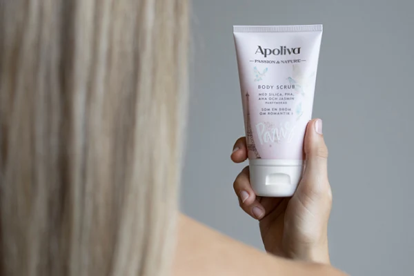 En kvinna håller upp en body scrub från apoliva. 