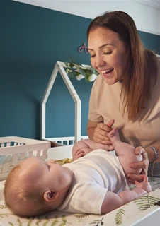 En mamma byter blöja på sitt barn. 