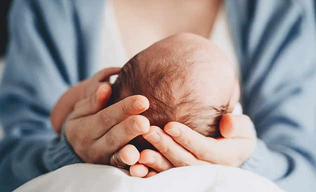 Mamma och myser med sin nyfödda bebis.