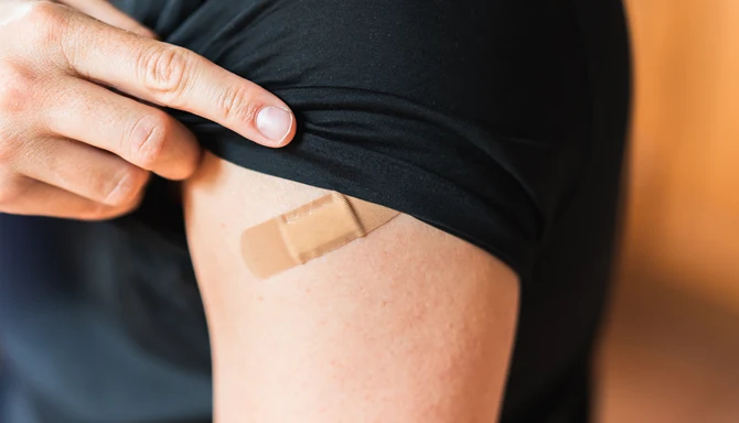 En person har precis vaccinerat sig och har ett plåster på armen.