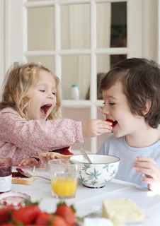 Två glada barn med celiaki som äter glutenfri frukost.