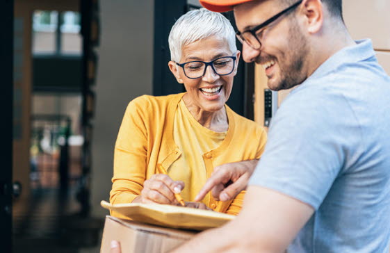 En man som levererar kylda varor från apoteket till en äldre kvinna.