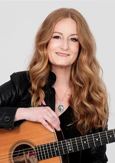 Anna Stadling sitter på en pall med en gitarr. 