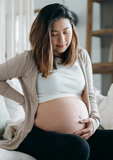 En gravid kvinna som sitter på en soffa.