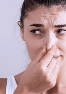 En kvinna som håller för sin näsa. 