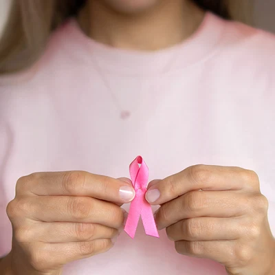 En kvinna som håller fram en rosa bandet rosett.