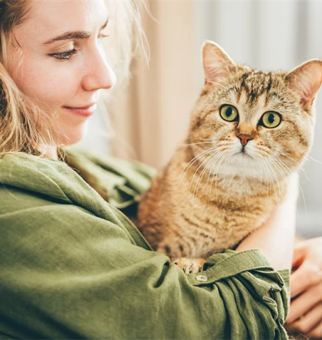 Kvinna och katt som myser tillsammans i soffan.
