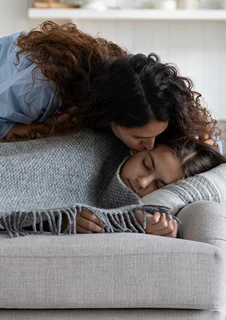 En mamma bäddar om sin sjuka dotter i en soffa. 