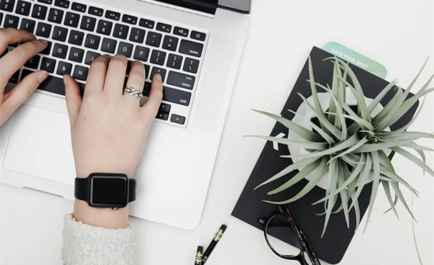 En person med apple watch som skriver på sin dator.