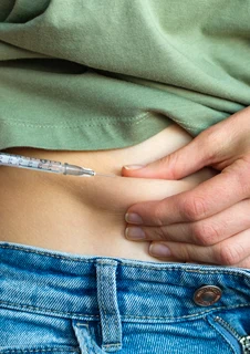 En kvinna med diabetes ger sig själv en insulininjektion med en engångsspruta med en liten nål.