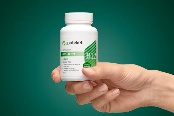 En hand visar upp kosttillskottet "B-VITAMIN" från apoteket.