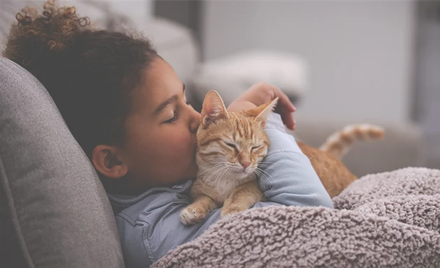 Tjej som gosar med en katt. Något personer med kattallergi tyvärr måste avstå.