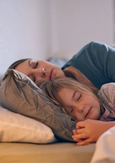 En mamma kramar om sitt barn i en säng. 
