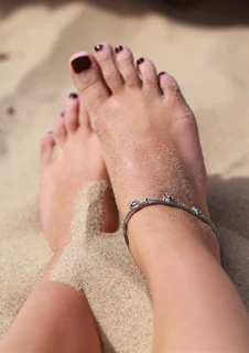 Ett par fötter i sand. 