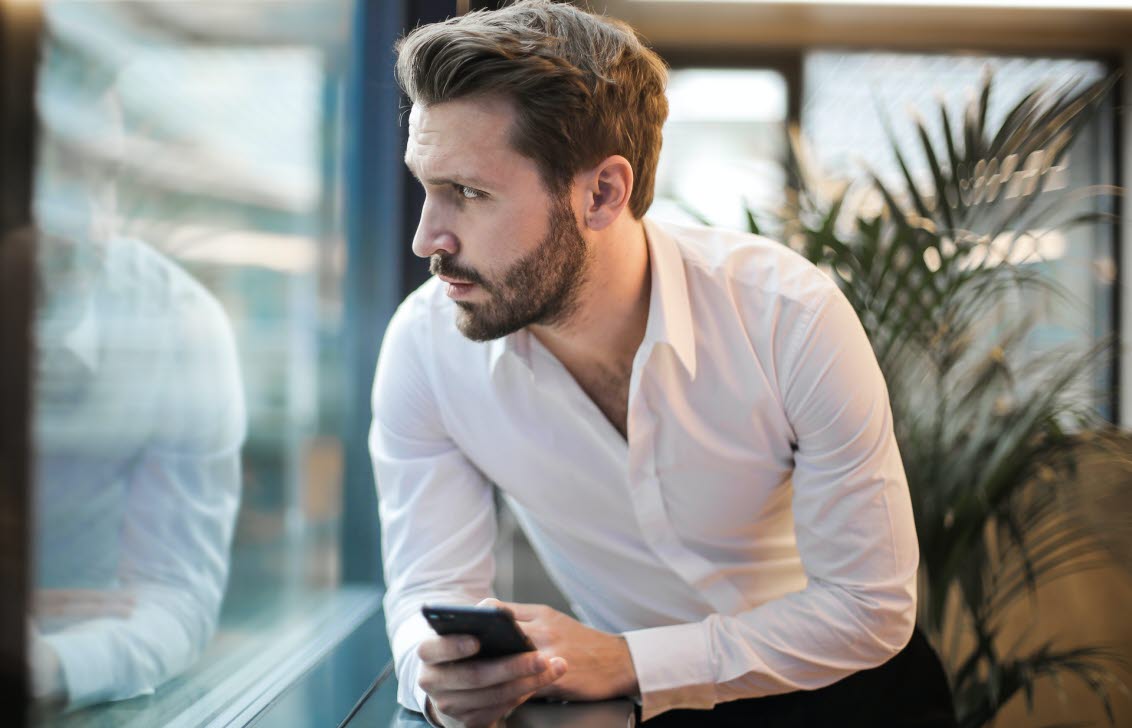 Stressad kille med mobilen i handen.