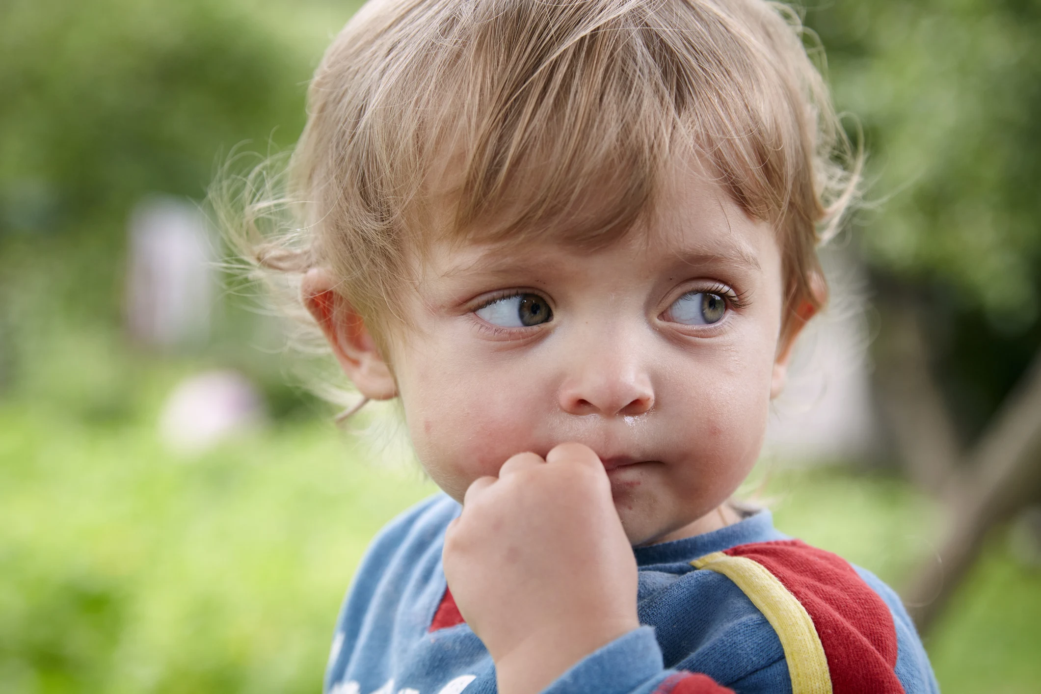 Litet barn med fingrarna i munnen.