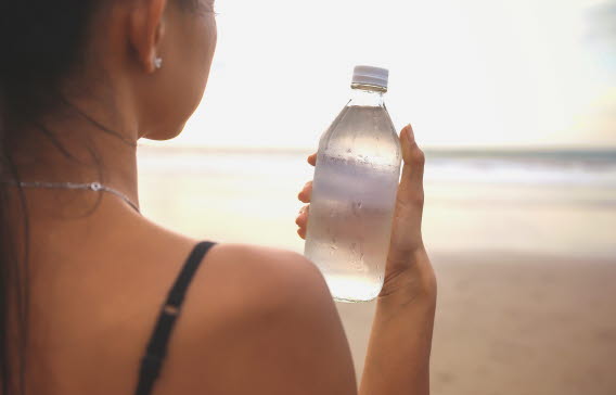 En person som håller i en vattenflaska på stranden.