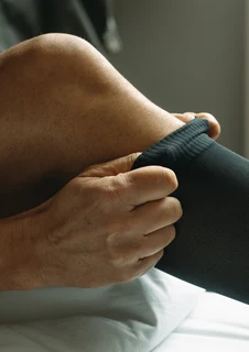 Kvinna som sätter på sig strödstrumpor, något som kan motverka åderbråck och svullna ben.