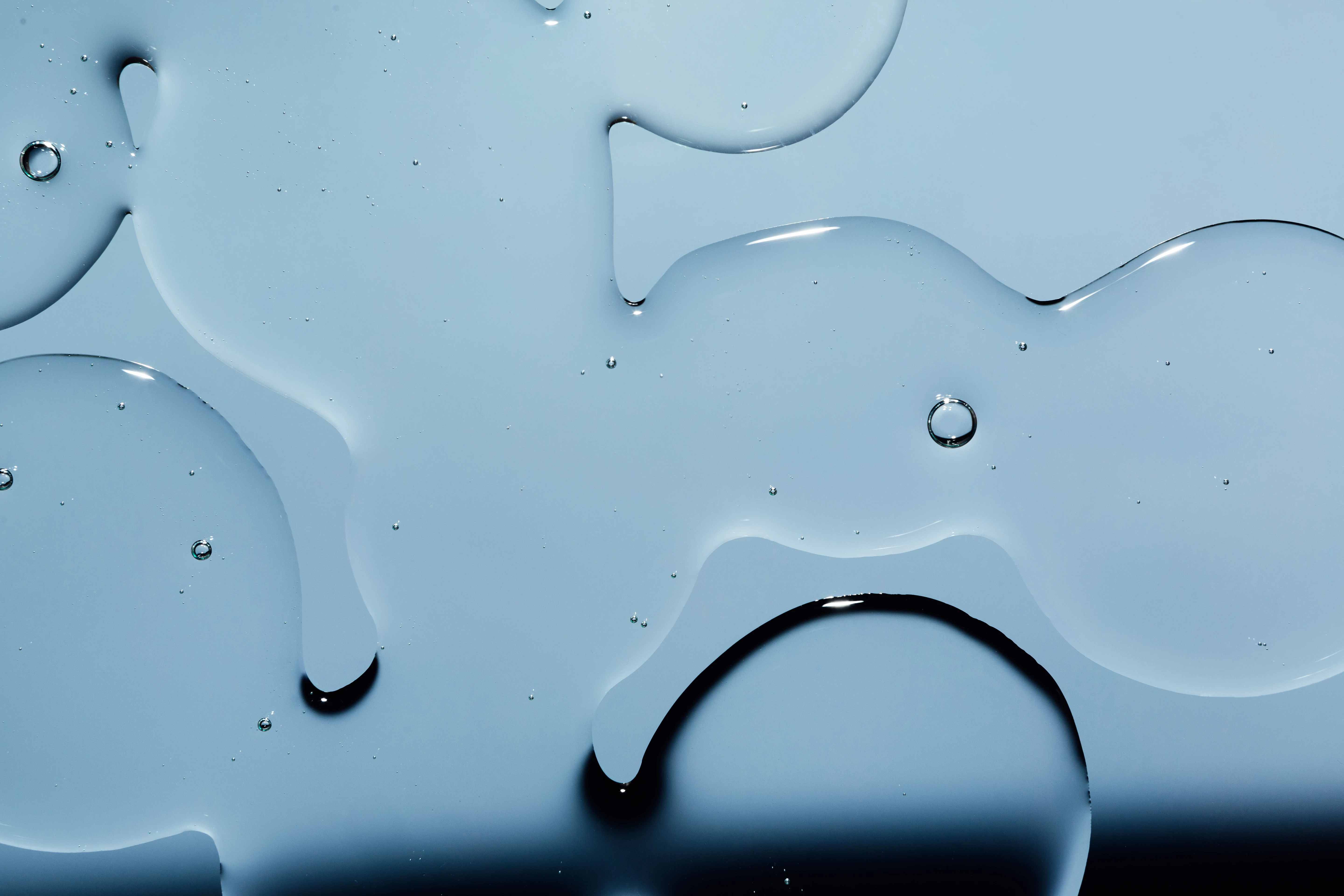 Närbild på transparenta vätskedroppar på en slät, blå yta.