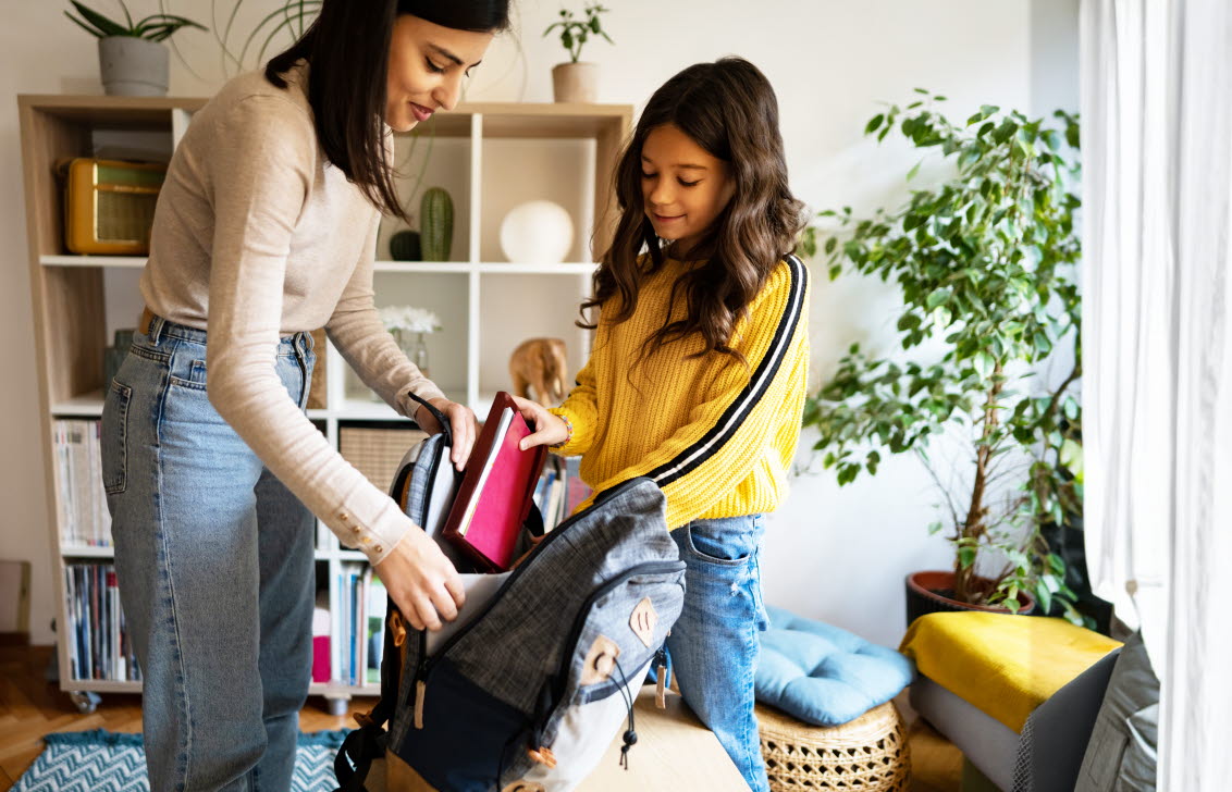 Flicka med ADHD som får hjälp av sin mamma att packa till skolan.