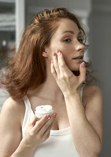 Kvinna som applicerar kräm för att skydda hudbarriären.