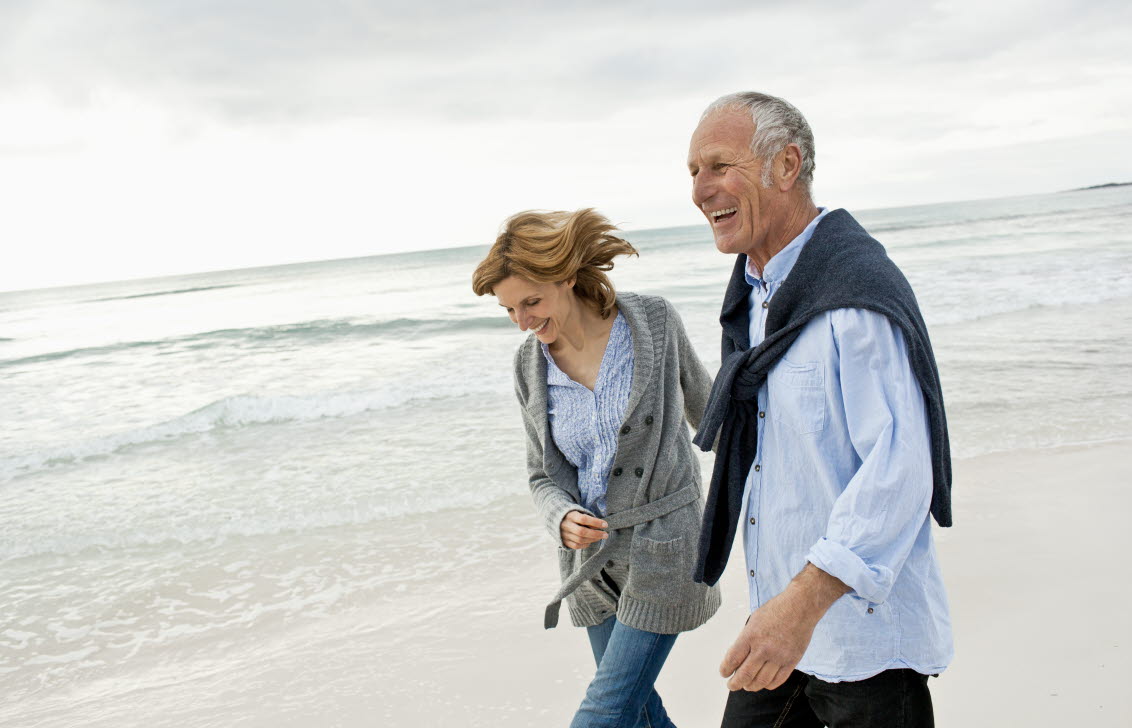 En man och en kvinna promenerar på stranden.