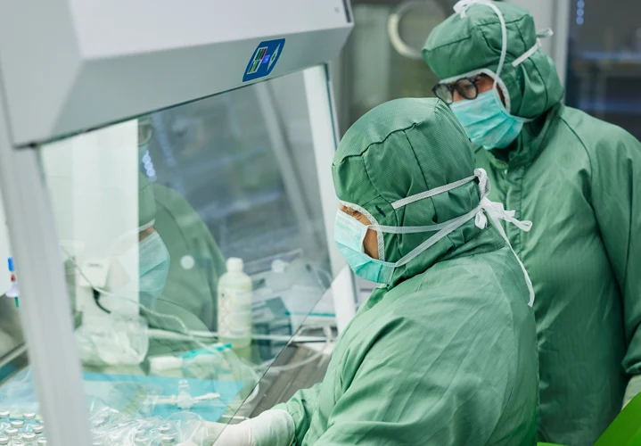 Två personer arbetar i ett laboratorium, båda har skyddskläder på sig