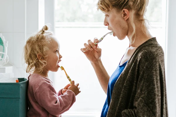 En mamma som borstar tänderna tillsammans med sitt barn.