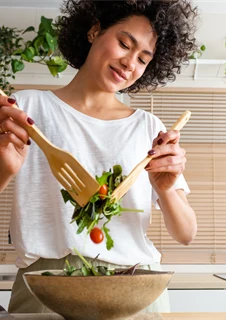 En kvinna som gör en sallad i sitt kök.