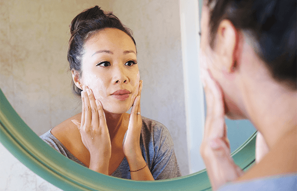 Kvinna som applicerar exfoliering i ansiktet.