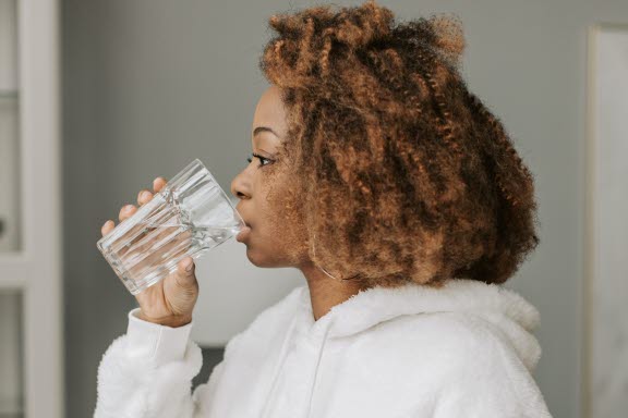 Kvinna med halsont som dricker vatten.