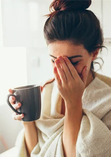 En kvinna håller ena handen framför ansiktet för att dämpa smärtan från hennes bihåleinflammation. 