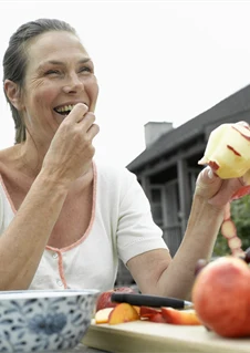 Kvinna som äter ett äpple - ett vanligt livmedel du kan vara korsallergisk mot.