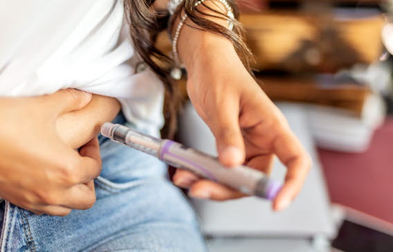 	En kvinna tar en insulinspruta i magen för att behandla sin diabetes.