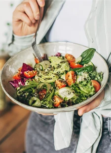 Kvinna håller i en skål med sallad med grönsaker och baljväxter, lämplig för personer med typ 2-diabetes.