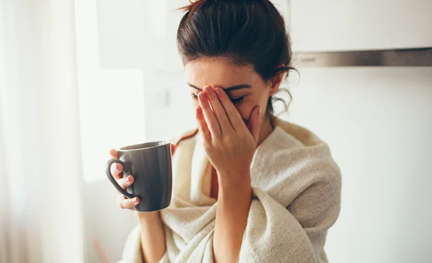 En kvinna håller ena handen framför ansiktet för att dämpa smärtan från hennes bihåleinflammation. 