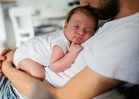 En pappa som håller om sin bebis. 