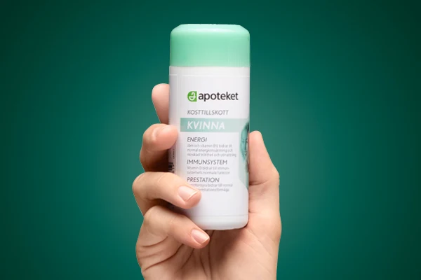 En hand visar upp kosttillskottet "KVINNA" från apoteket.