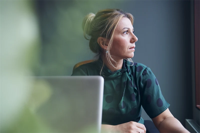 En kvinna sitter framför en dator och ser oroad ut 