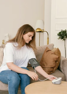 En kvinna mäter sitt blodtryck på egen hand med blodtrycksmätare.
