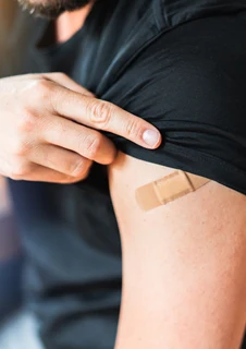 En person som precis vaccinerat sig och har ett plåster på armen. 