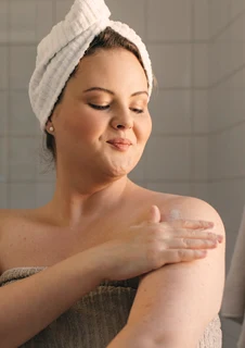 En kvinna som smörjer in sin arm med hudlotion.