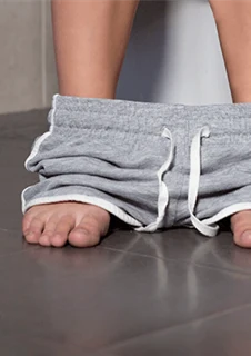 En person sitter på toaletten. 