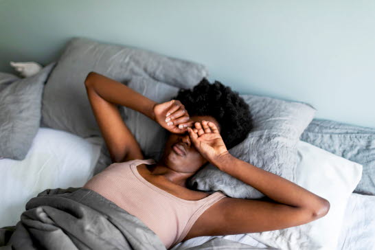 En kvinna som sträcker på sig i sängen.