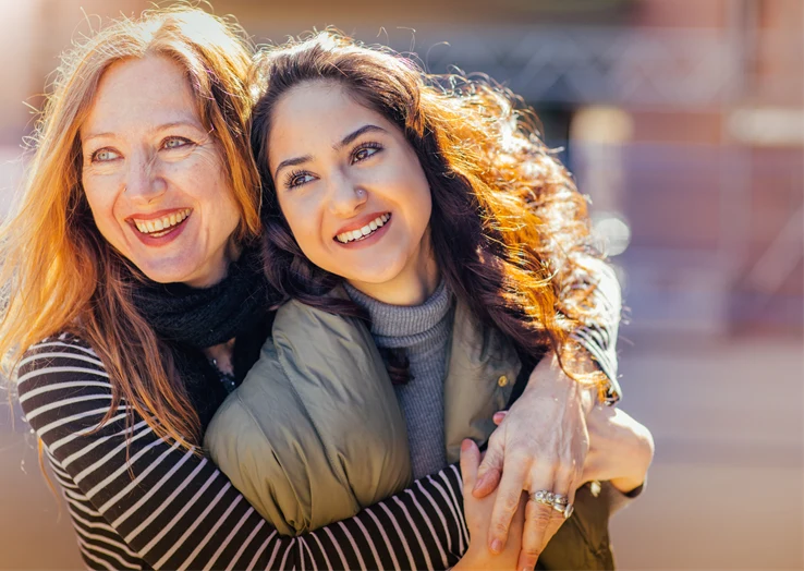 Två kvinnor kramar om varandra i solen.