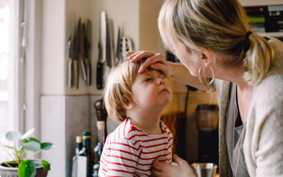En mamma känner på sin lille sons panna för att kontrollera om han har feber.